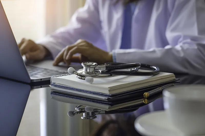 Doctor in white lab coat on laptop