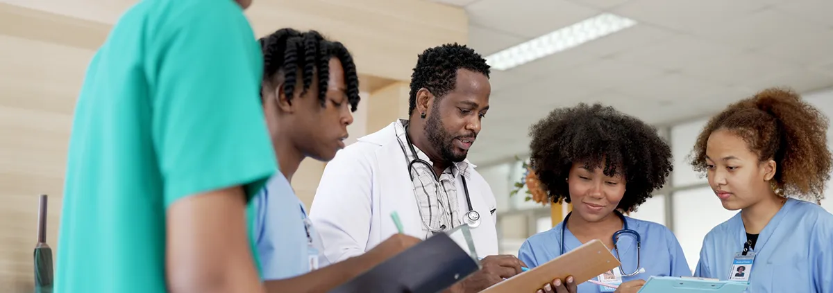 Male doctor and team of nurses reviewing clipboard in hospital