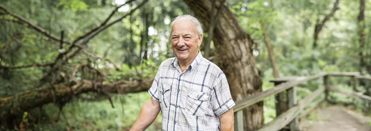 Older person standing on a bridge in the woods