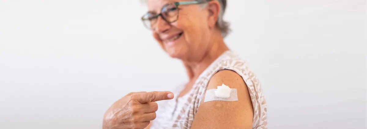 Senior smiling while showing a vaccine shot on arm